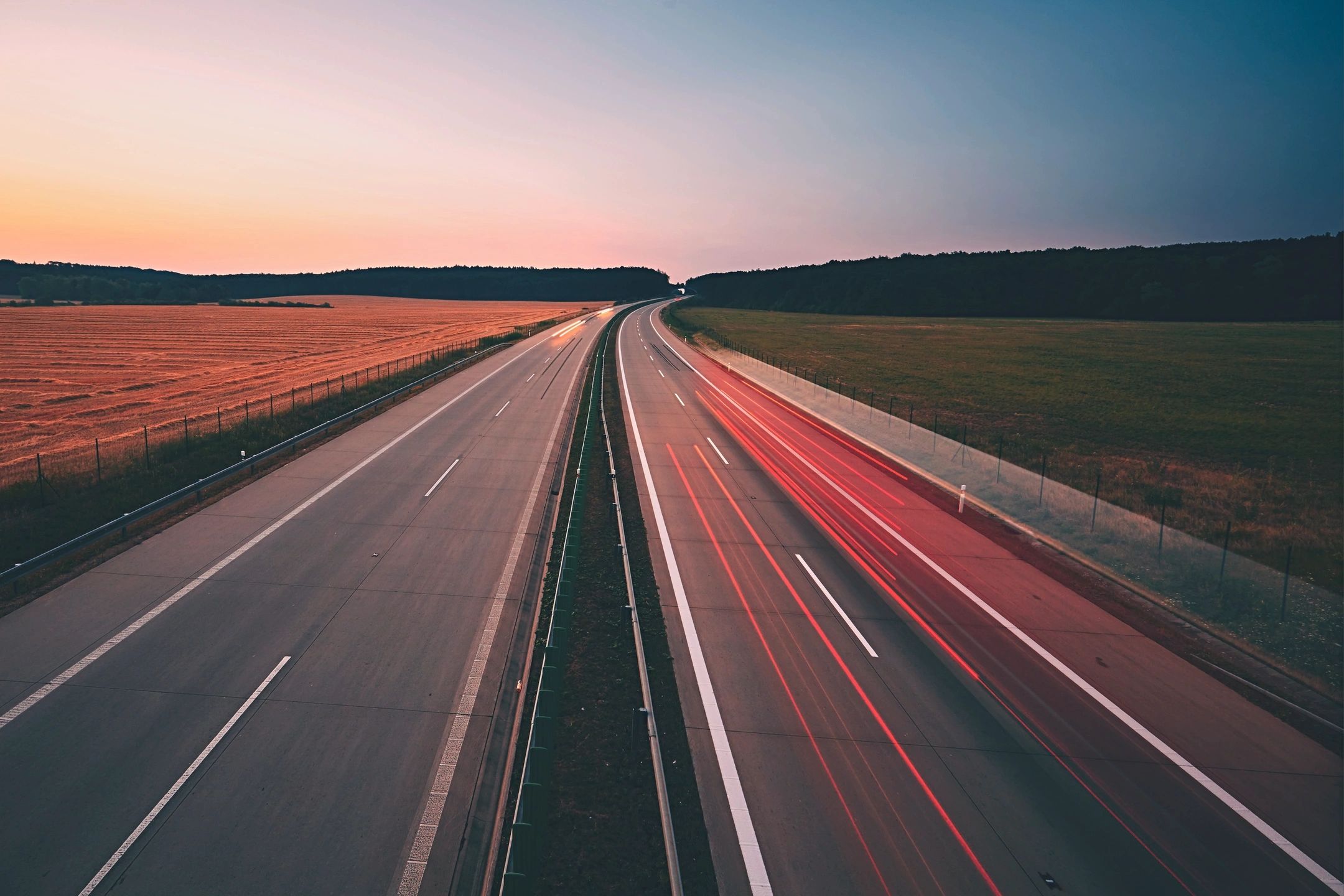 Empty highway with car light trails at dusk