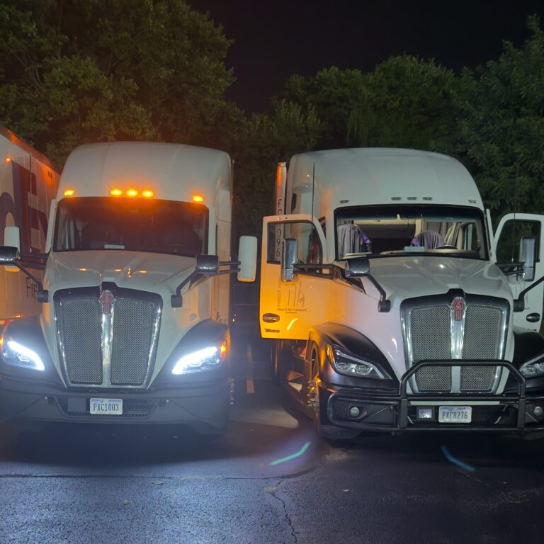 Two white semi trucks parked at night