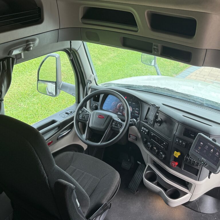 M2GT Inside view of a truck driver's cabin with dashboard and steering wheel.
